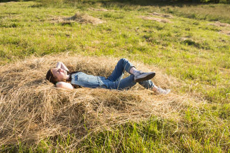 A young girl with a smartphone is relaxing in nature on a Sunny summer day.の写真素材