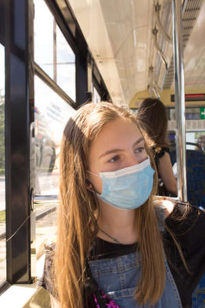 A teenage girl rides public transport in a medical mask during the covid-19 pandemicの写真素材