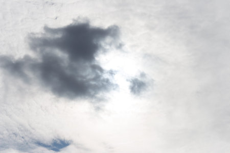 Cloudy sky. The sun is covered by a gray cloud. Weather change. Approaching rain front.