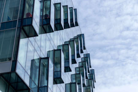 Abstract a fragment of modern architecture, walls of glass with balconies on a background of blue cloudy sky.の写真素材
