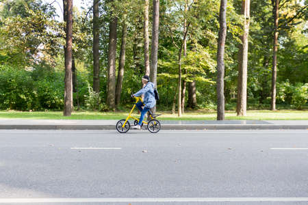Russia, Moscow, Oktober 11, 2020: A woman rides a Bicycle on the road of the city forest, Park. Alternative eco-friendly mode of transportation.のeditorial素材