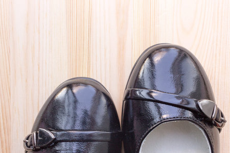 pair of black patent leather shoes on wooden background, copy space