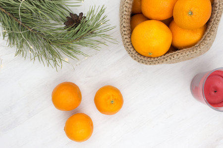 Fragrant tangerines in a knitted jute basket on a wooden table.