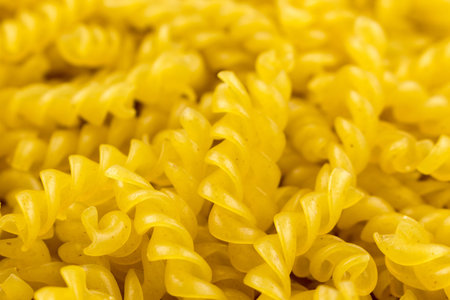 Raw pasta fusilli. spiral shape pasta, yellow background