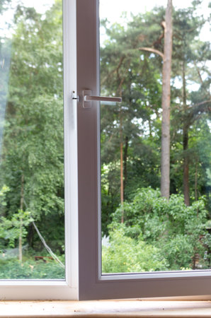Plastic window in the house with a view of the pine forest.