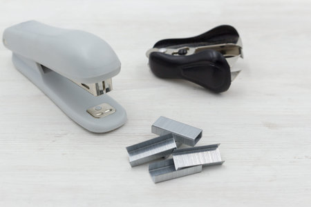 Gray stapler, anti-stapler with clerical staples on a white wooden background. office stationery.