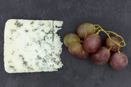 Cheese with blue mold on a black slate board, close-up. Delicious dairy product, delicacy.の写真素材