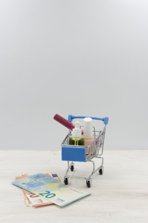 Cosmetics in the shopping cart and Euro Money on a white wooden tableの写真素材