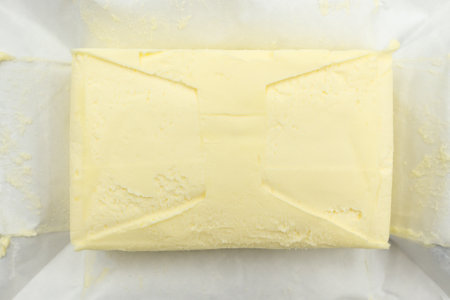 Fresh piece of butter on the packaging paper closeup. Butter of industrial production, bought in a store.の写真素材