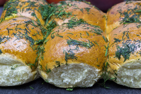 Rich, fluffy fresh buns with garlic and dill on a black kitchen board