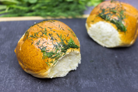 Two rich, fluffy fresh buns with garlic and dillon a black kitchen board