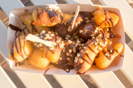 Greek lukumades donuts with pistachio-nut sauce in a cardboard tray.