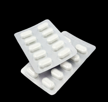 Two white medicine tablet in blister pack with front pack packaging isolated on black background.