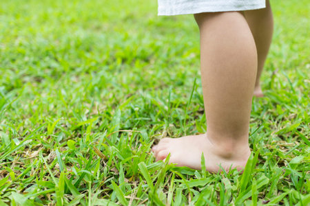 Baby's foot stepping on the grass in the morning.