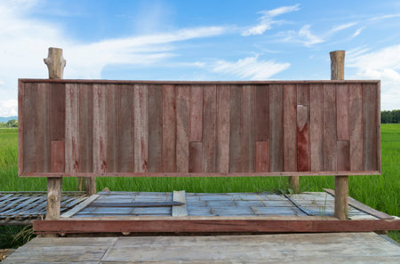 Old wooden blank sign with blue sky and green paddy, Vintage wood post board for decoration work with copy space.の写真素材