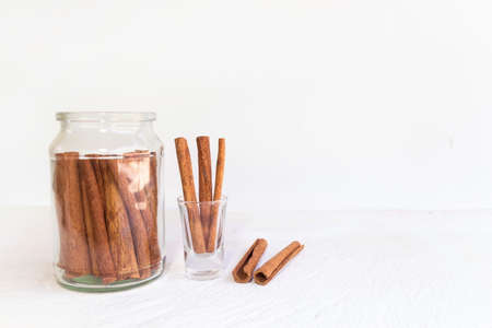 Cinnamon in glass and cinnamon sticks on white wooden table and white background, image with copy space.の写真素材