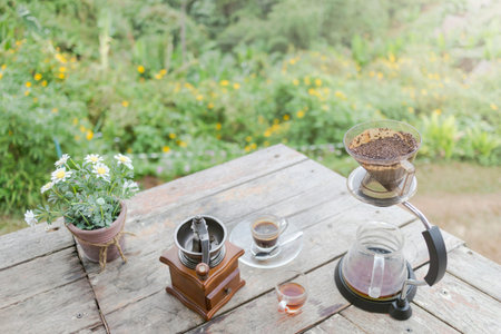 Morning cup of coffee with Rotary Coffee Grinder and Flower Pot on the wooden table with Tree and...