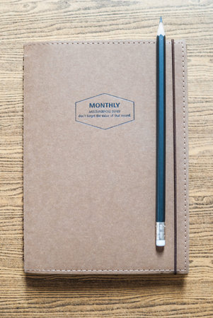 recycled paper notebook with a pencil on wooden backgroundの写真素材