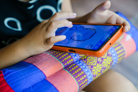 Young girls playing mobile phones on the road or the house cause an accident Or using mobile phones for a long time may cause damage to the eyes Hazardous concepts for children's mobile phonesの写真素材