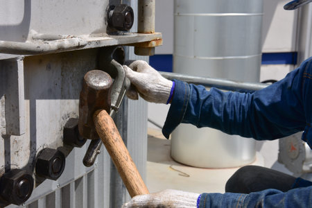 Workers use a wrench to loosen the nut by using a large hammer.  To open the metal manhole. The...