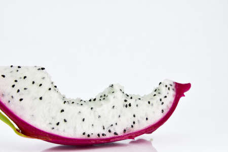 Close up the dragon fruit that is bitten on white background. Dragon fruit is popular as a fresh fruit.Is a mixture of fruit salad or blended into juice.の写真素材