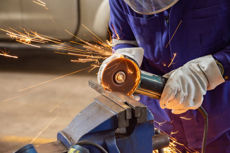 workers cutting metal sheets with electric grinder in the workshop.Mechanic wear personal protective...