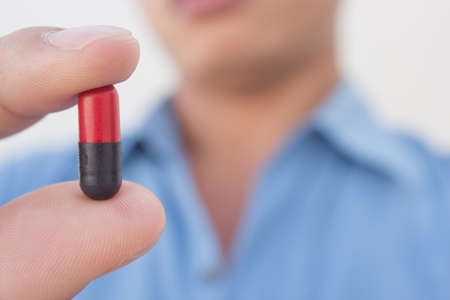 young man showing pill close upの写真素材