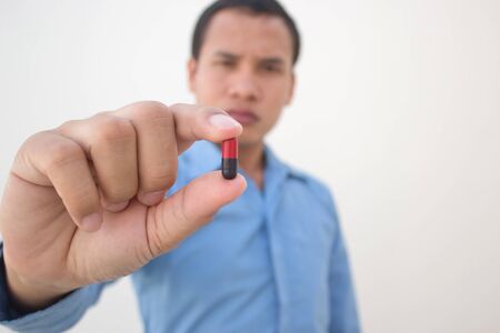 young man showing pill close upの写真素材