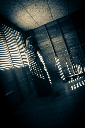 Ghost girl in haunted house,Mysterious girl in black dress dragging an axe in abandon houseの写真素材