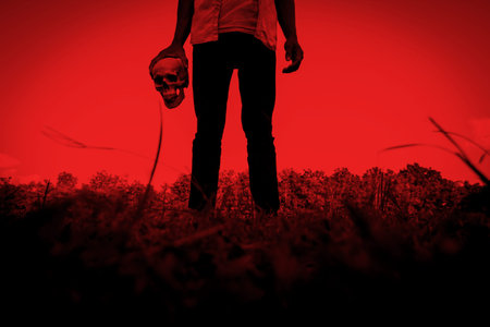 Release evil,Person with human skull in hand,Scary background for halloween and book cover ideasの写真素材