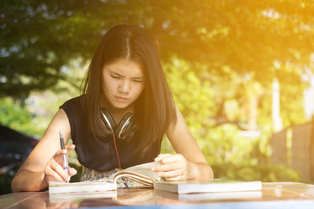 Asian teen student reading book preparing for exam