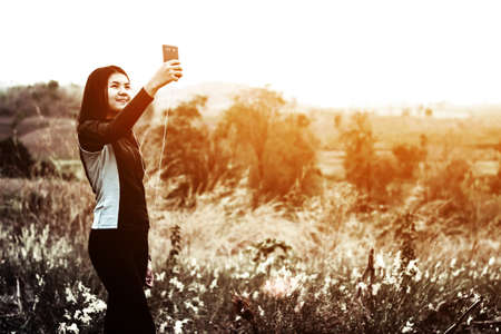Woman taking photo of sunset by using smart phoneの写真素材