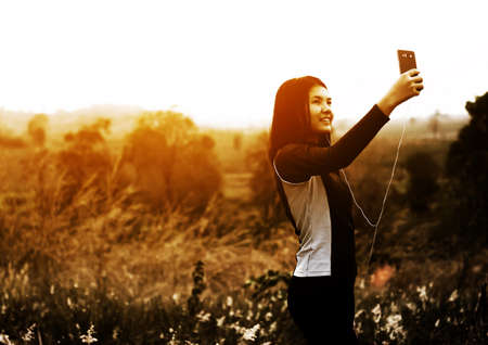 Woman taking photo of sunset by using smart phoneの写真素材