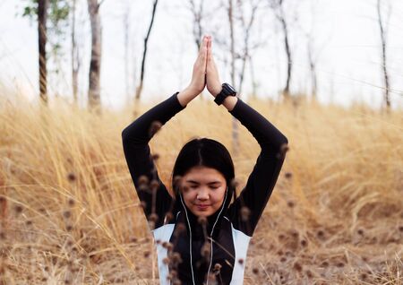 Asian woman meditating in grass fieldの写真素材