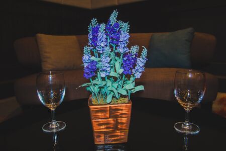 The centre table of the living room sofa set With a glass of water and decorated with blue flowers in a brown pot For beauty, With a background as a sofa set for living roomの写真素材