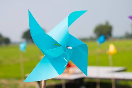 Blue toy windmill with four points With a background image of lush green fields On a clear day and clear skyの写真素材
