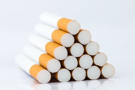 Closeup of many cigarettes The cigarette end is brown and the tip is white. Arranged in a triangle On a white backgroundの写真素材
