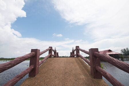 The cemented bridge connects the path to the lake in the middle of the water on a clear day. In beautiful natureの写真素材