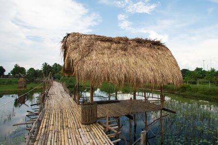 A wooden hut in the middle of the water and a wooden pathway connecting to the resting spot Thatched roof According to the way of life of people living in southern Thailandの写真素材