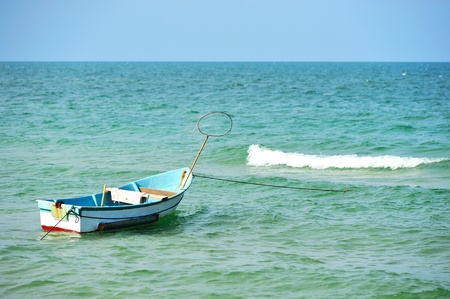 Small boat tethered on shore and beautiful blue oceanの写真素材