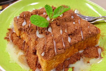 Toasted bread topped with cocoa powder and condensed milk, decorated with mint leaves