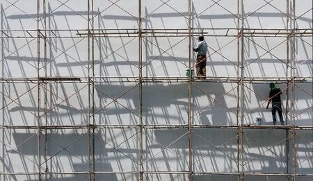 men climb scaffolding ,they paint  new colors buildingのeditorial素材