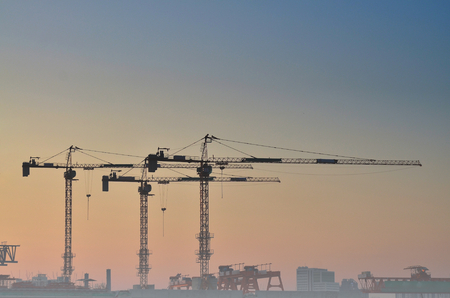 Large construction site including several cranes working on a building complex, with clear blue sky and the sunのeditorial素材