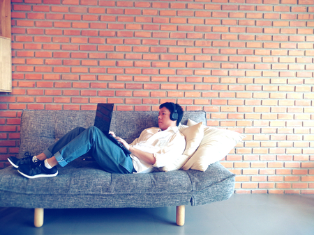 side view of cheerful Thailand man using laptop at homeの写真素材