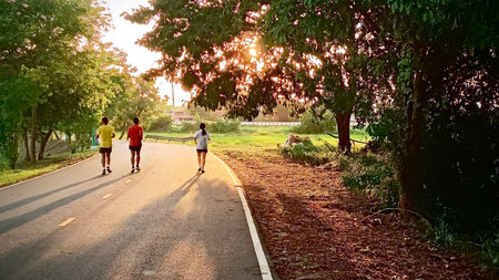 Running in the park at sunset. Group of people jogging outdoors.