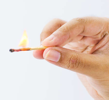 Hand holding a fired matchstick on a white backgroundの写真素材