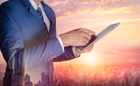 Businessman with digital tablet on blurred city backgroundの写真素材