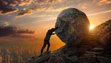 Business man pushing large stone up to hill , Business heavy tasks and problems concept.の写真素材