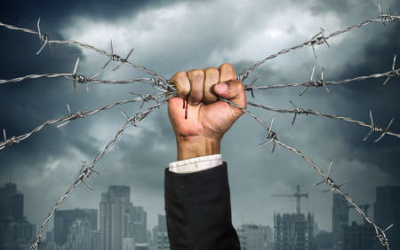 Hand of businessman holding on a barbed wire , Business heavy tasks and problems concept , Business risk concept.の写真素材