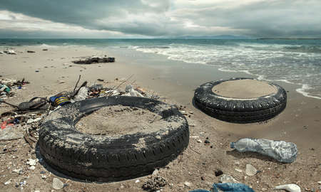 Car tire and plastic bottles pollution in muddy puddle on beach. (Environment concept)の写真素材